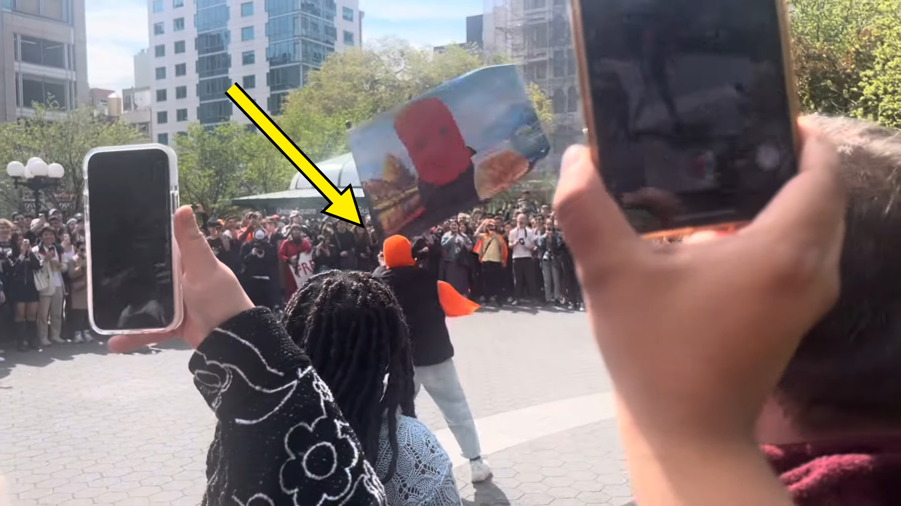 Crowd watching a performer, some audience members hold up phones to record the event