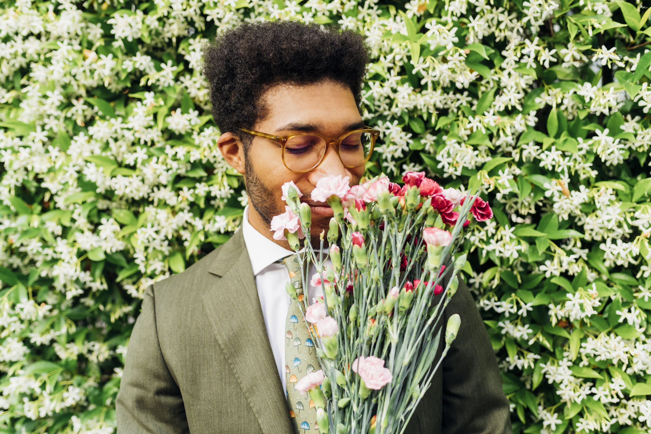 Person holding a bouquet in front of their face against a floral backdrop