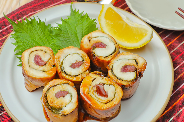 皿に盛られたウナギの肉巻き、添え物にレモンと青葉。