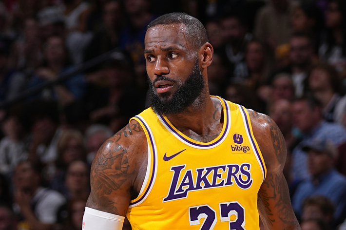 LeBron James in Lakers uniform mid-game, expression focused, on the basketball court