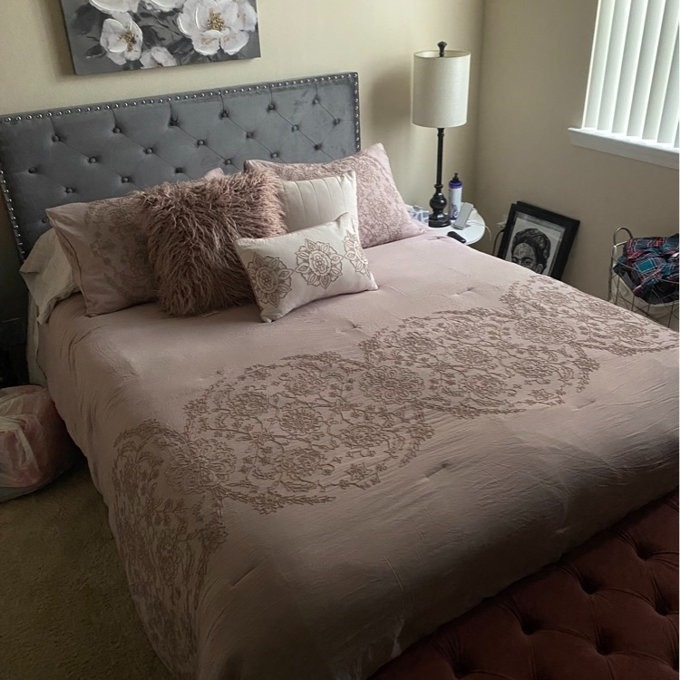 Bed with an ornate comforter and assorted pillows in a bedroom setting for a shopping article
