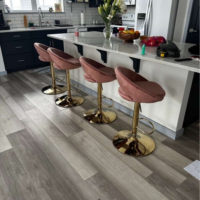Three modern bar stools with pink upholstery and gold bases in a contemporary kitchen