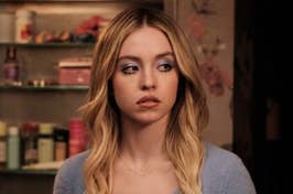 Sydney Sweeney standing in a room with shelves, looking thoughtful