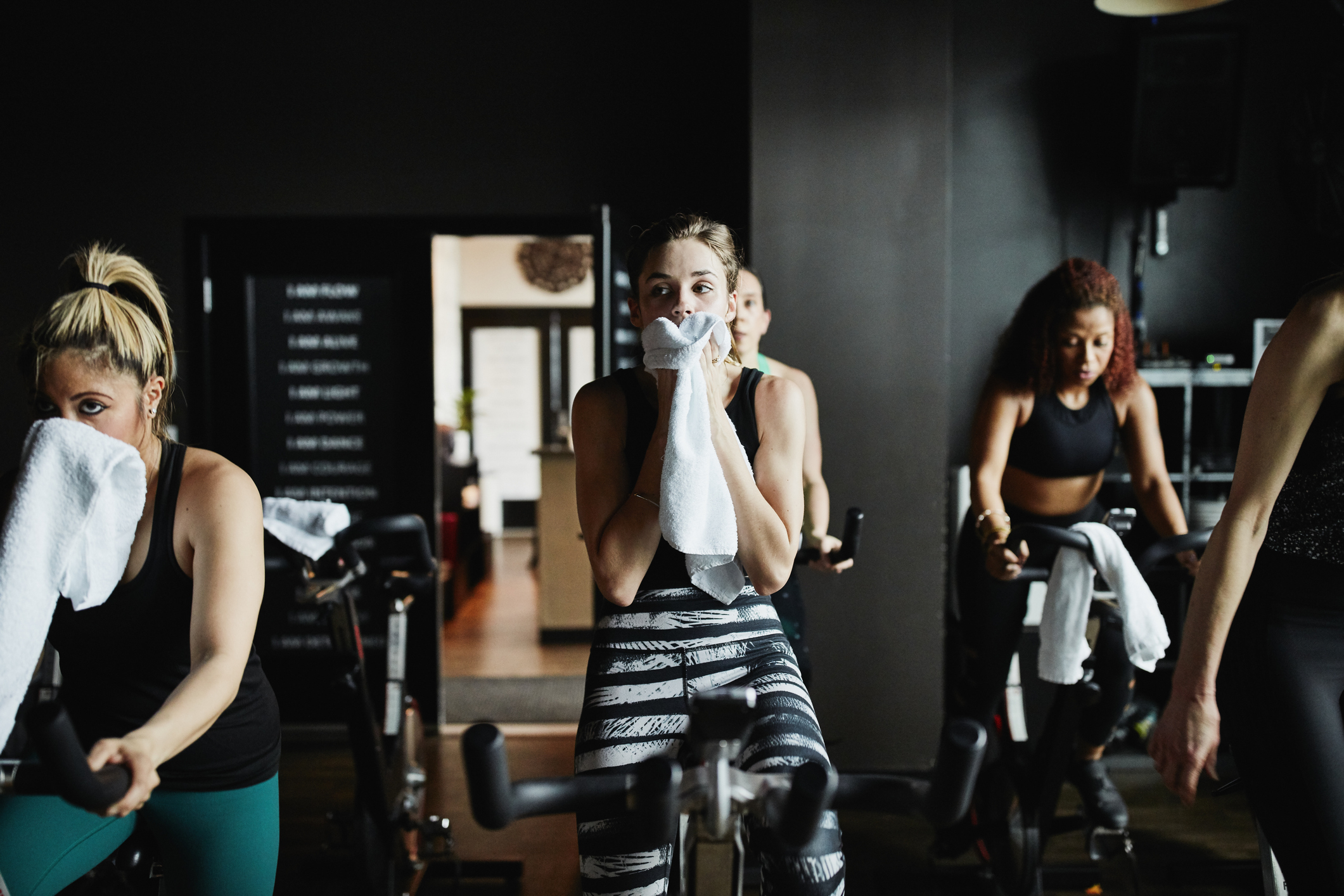 Three people wiping sweat with towels during a gym workout session