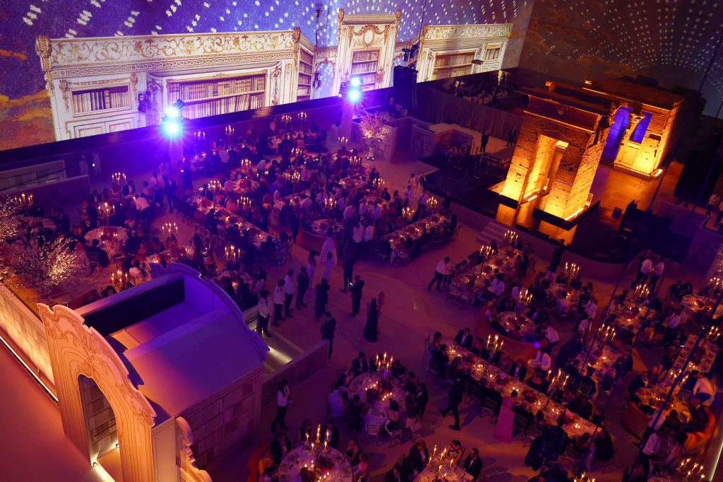 Overhead view of a grand, elegant event hall filled with guests seated at tables, ambient lighting, and opulent decor
