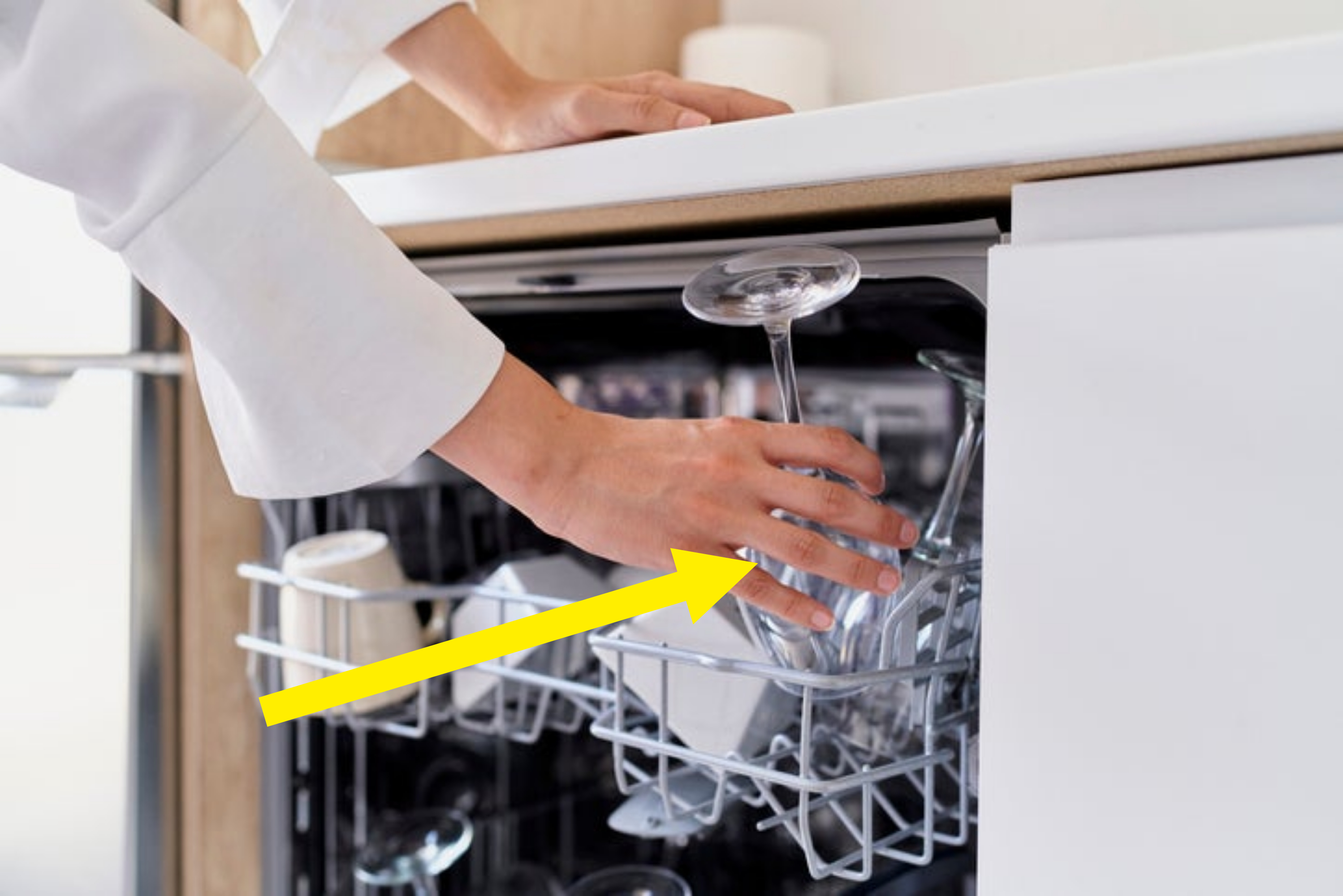 Person loading dishwasher with clear stemware