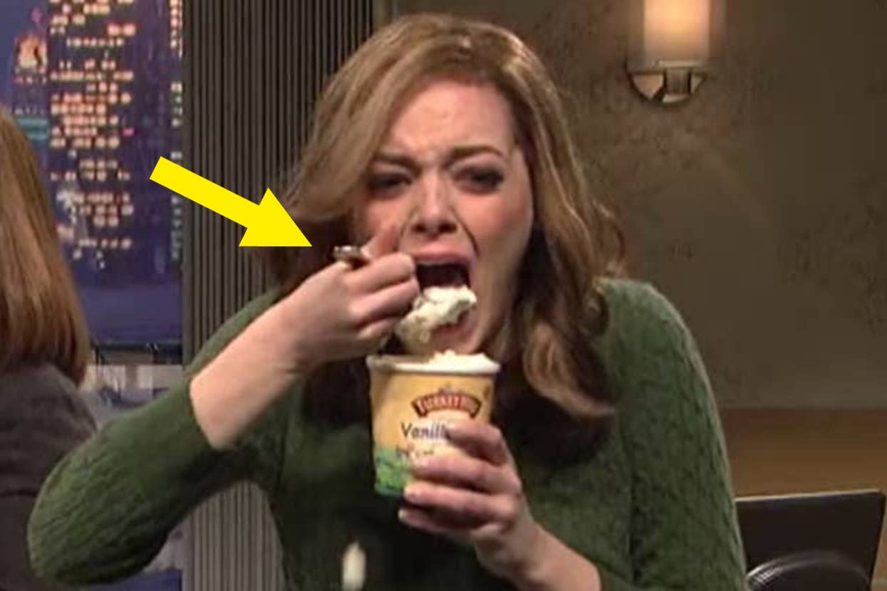 Woman in green sweater eating vanilla ice cream from a container, looking emotional