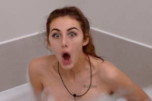 Person with a surprised expression sitting in a bubble bath