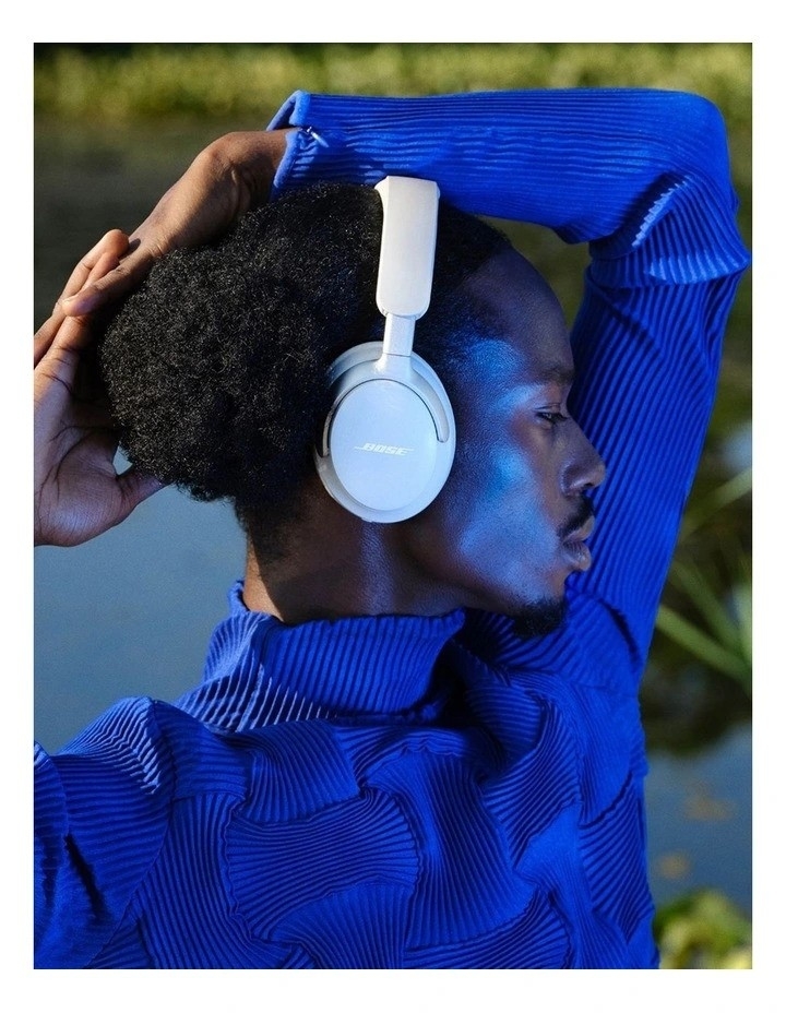 Person with headphones and a striking blue top posing in a relaxed manner