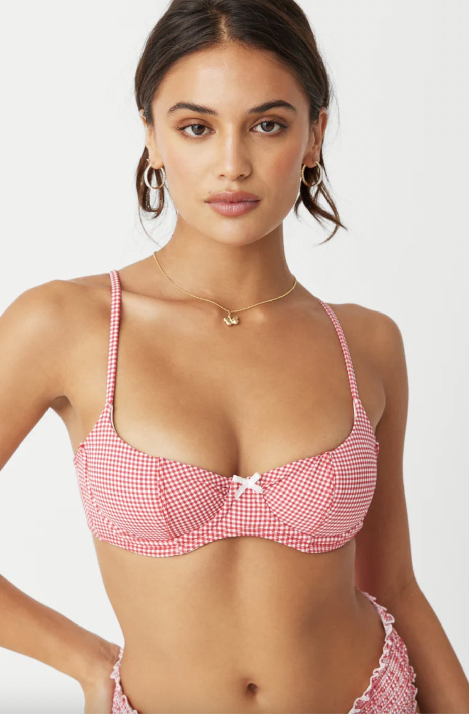 Wanita dengan atasan bikini kotak-kotak dengan simpul depan, kalung emas, dan anting melingkar