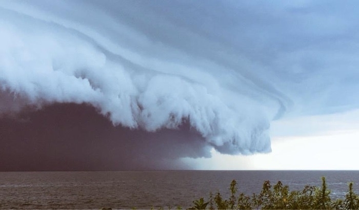 Imposing shelf cloud over the ocean horizon with a visible sky above