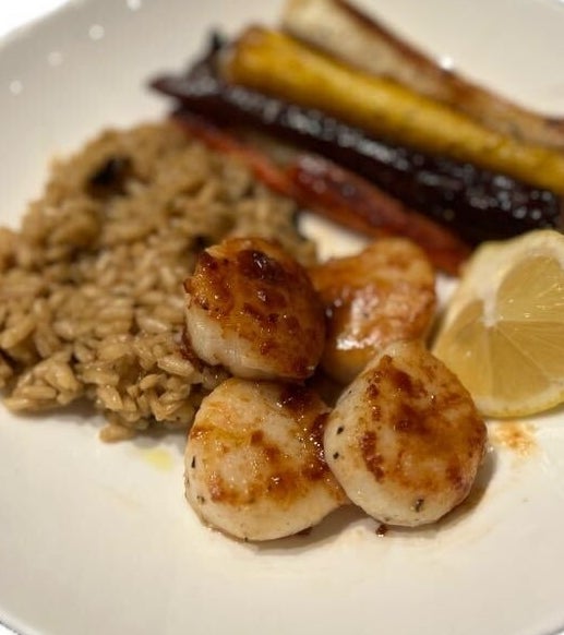 Plate with seared scallops, rice, roasted carrots, and a lemon wedge