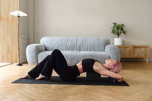 model using yoga block while laying down on yoga mat