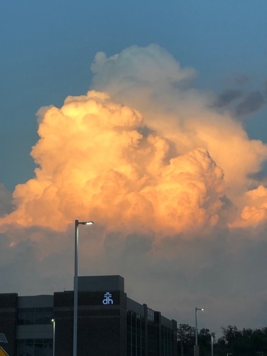 Cumulus cloud illuminated by sunset above a building