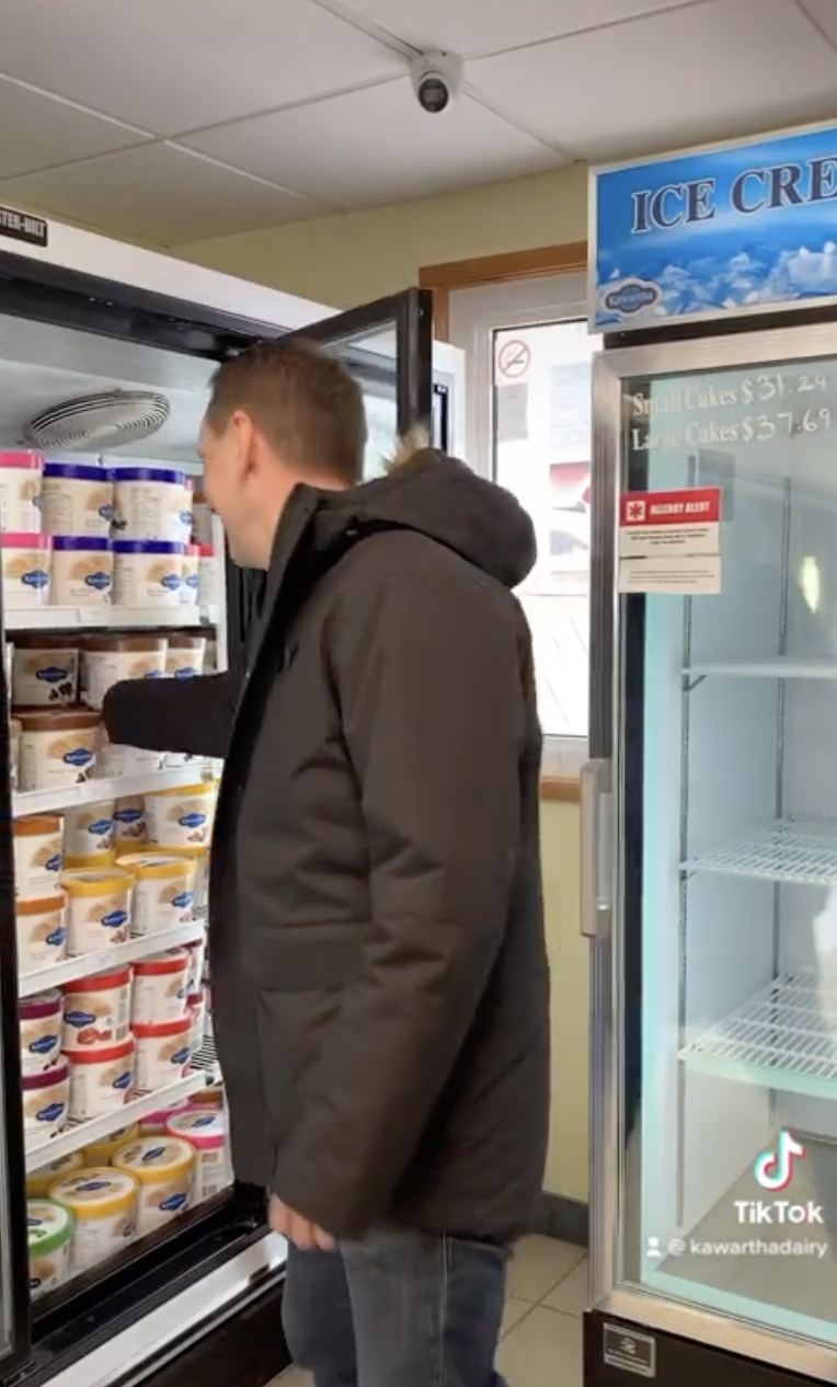 Person in a jacket looking at ice cream in a freezer at a store
