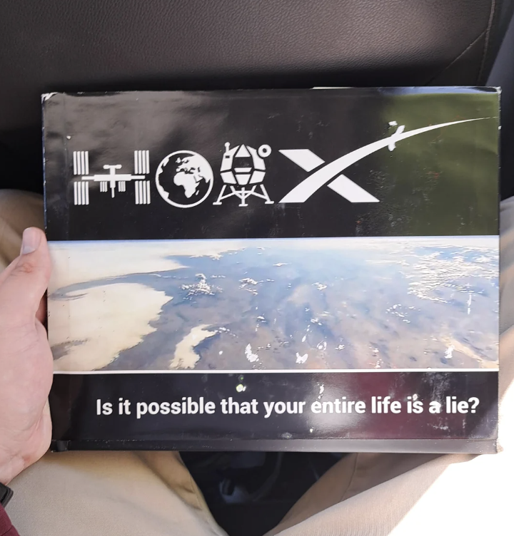 Box with various symbols and text &quot;Is it possible that your entire life is a lie?&quot; held in a person&#x27;s lap
