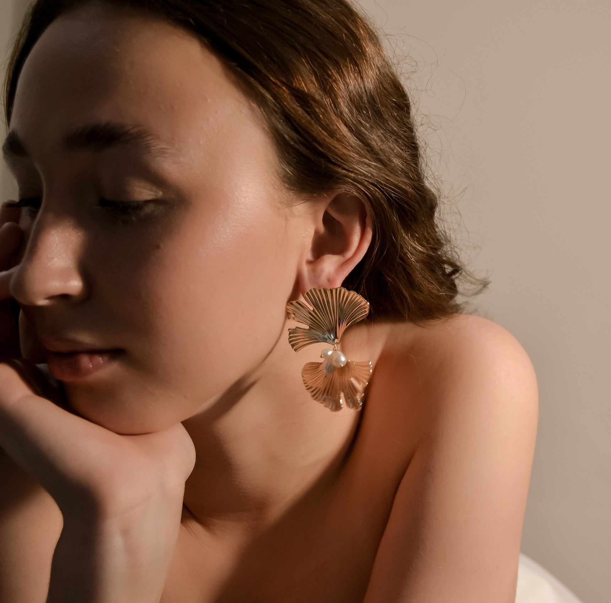 A person showcases a large, statement earring with a floral design