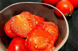 ボウルに入ったカットされたトマトと背景の全体トマト。