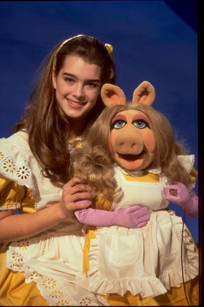 Brooke Shields and Miss Piggy from the Muppets, pose in matching dresses with white aprons