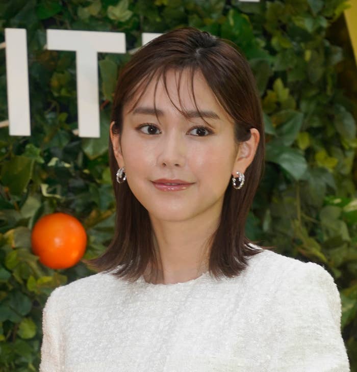 イベントに出席している女性が白い服を着て、短いヘアスタイルで笑顔をしています。