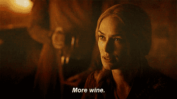 Cersei Lannister from Game of Thrones is seated at a table, requesting more wine