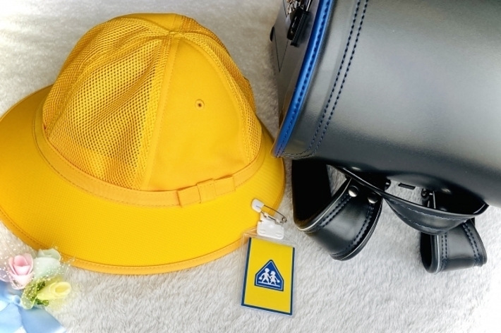 黄色のキャップと青いバッグ。バッグにはアクセシビリティマークが付いたキーホルダーがあります。