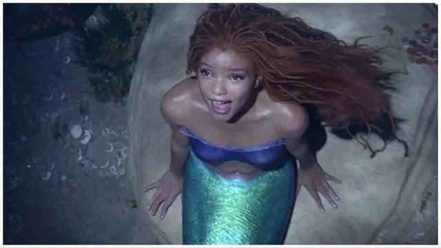 Ariel from The Little Mermaid, with long hair and mermaid attire, looks upwards with a surprised expression