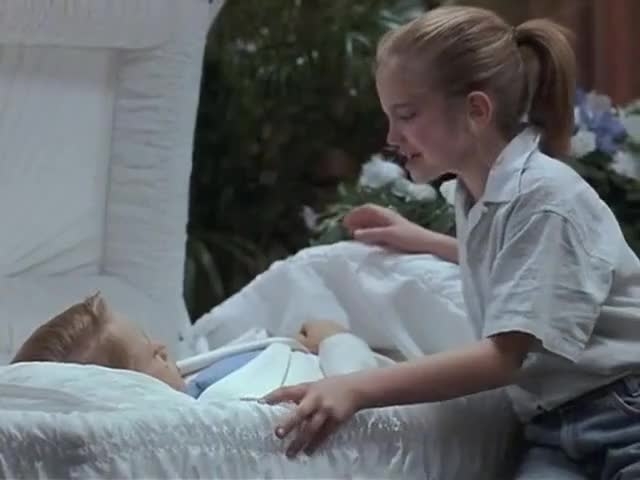 A girl comforting another child lying in a hospital bed