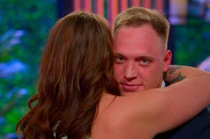 Two people from season 6 of "Love Is Blind" embracing — Chelsea and Jimmy — one facing the camera (Jimmy) making a face while Chelsea embraces him