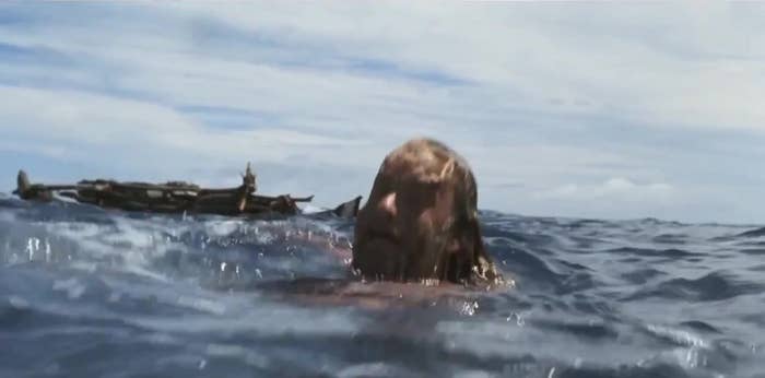 Person floating in the ocean with debris in the background