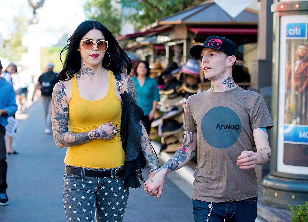 Kat Von D in a yellow top and star-patterned pants holds hands with Deadmau5 wearing a grey Analog tee