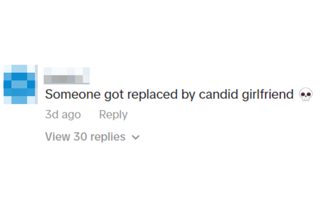 Text from a social media comment reading &quot;Someone got replaced by candid girlfriend&quot; with a skull emoji, indicating a humorous or shocking twist