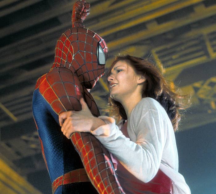 Spider-Man in costume rescues a woman, holding her as they appear mid-air