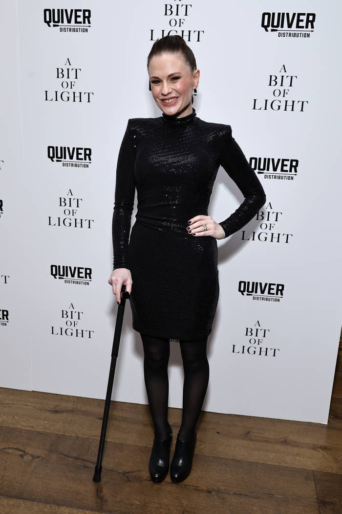 Anna in long-sleeve sequined mini dress with a cane, posing at an event
