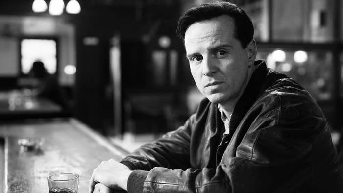 Andrew Scott in Ripley sitting at a bar with a contemplative expression; dressed in a leather jacket, the setting is indoors