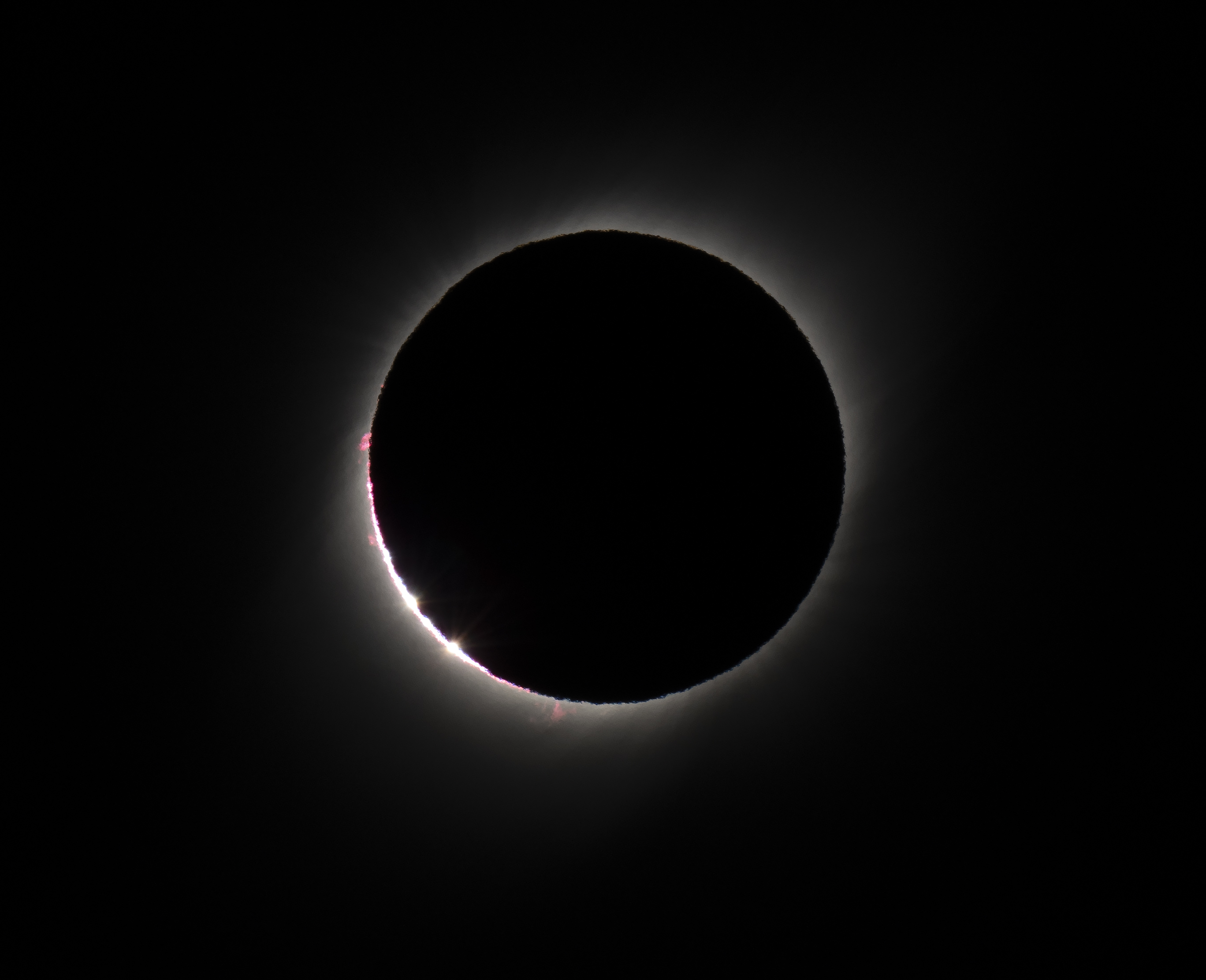 Solar eclipse with moon covering the sun, leaving a thin, bright outline visible