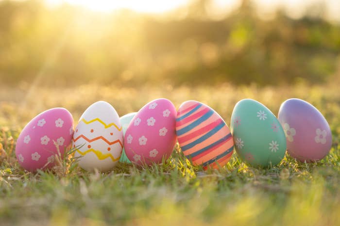 Five decorated eggs standing upright on grass with sunlight in the background
