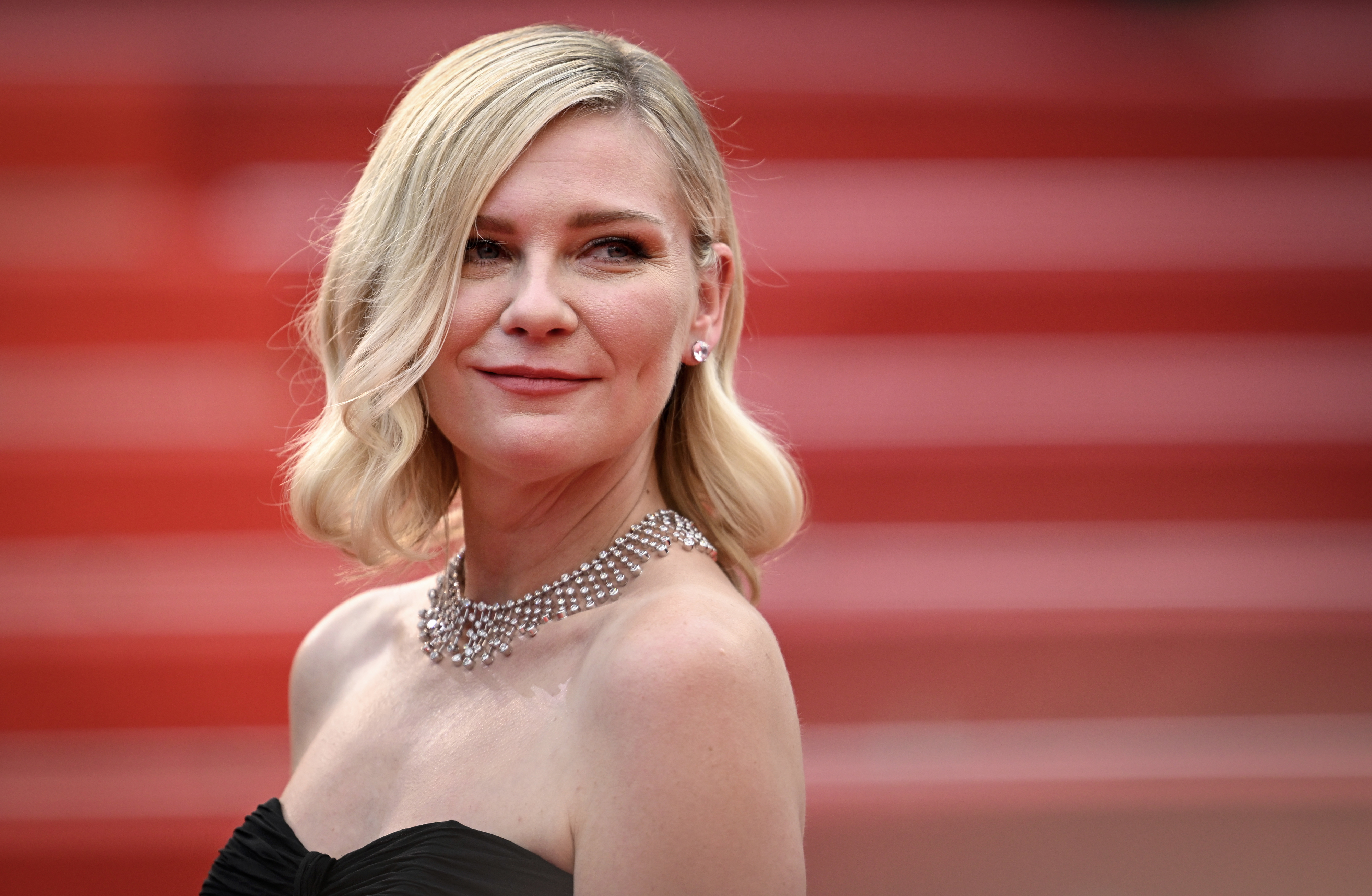Kirsten Dunst in strapless attire with a diamond necklace, posing at an event