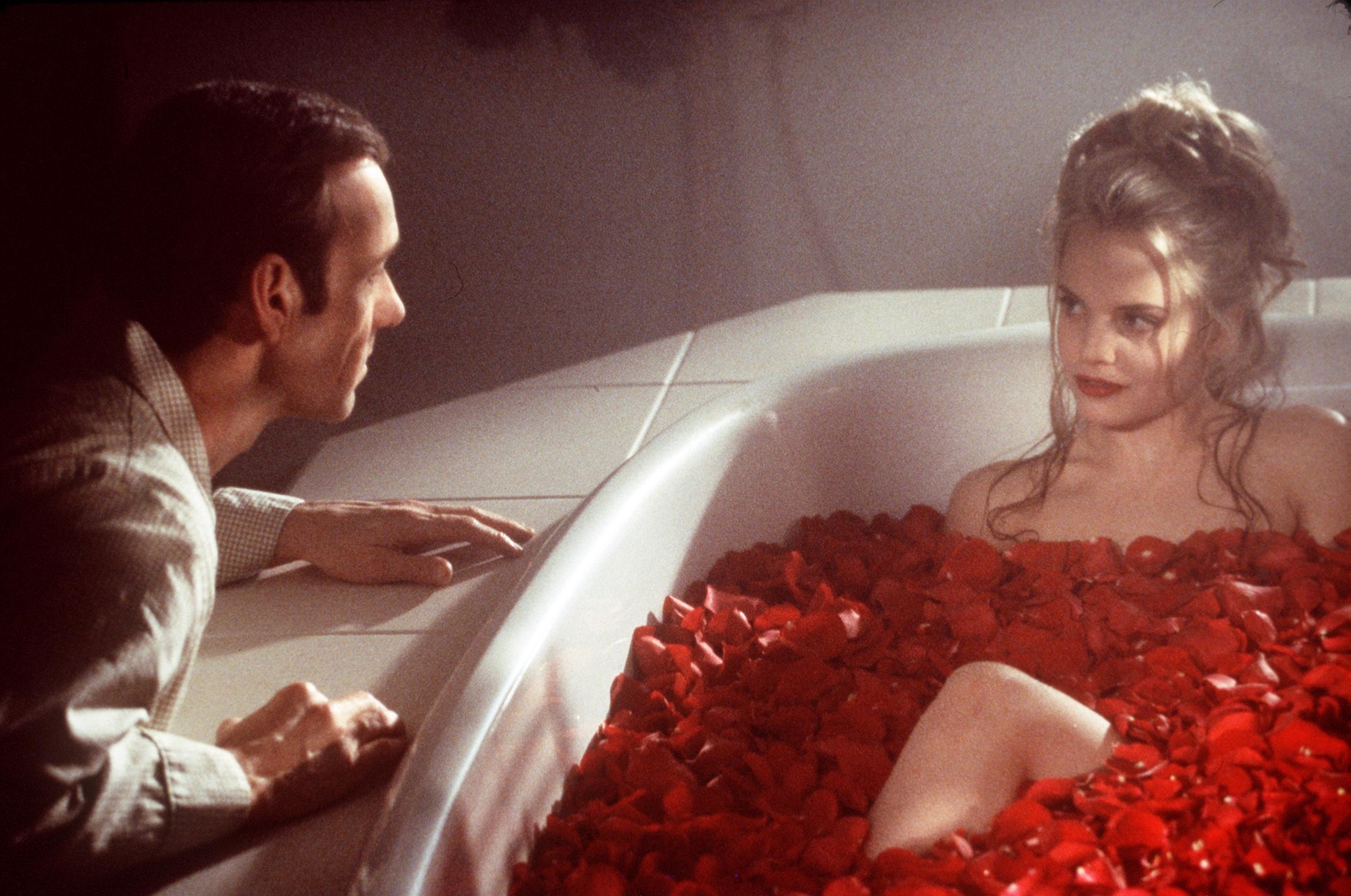 Kevin Spacey looking at Mena Suvari, who is in a bathtub filled with rose petals, in a scene from &quot;American Beauty&quot;