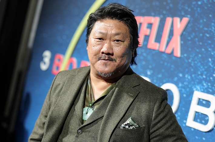 Benedict Wong at event, in a stylish suit with a patterned pocket square and pendant necklace