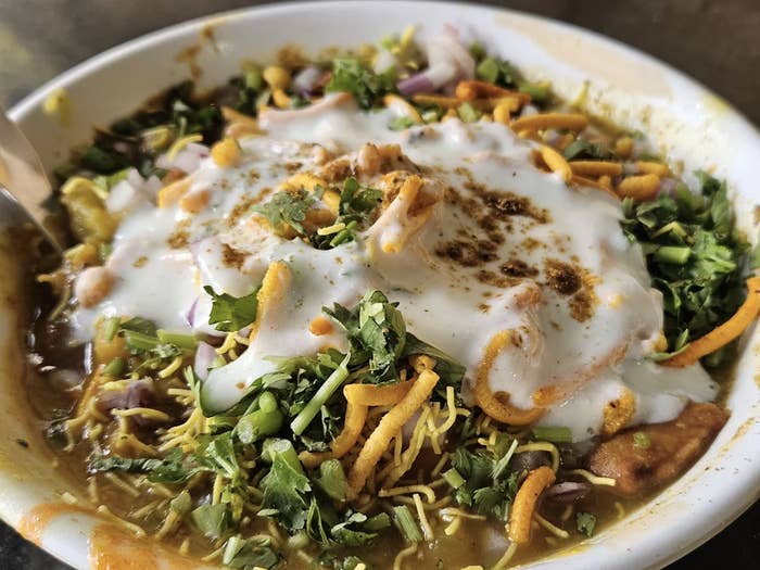 A bowl of Indian chaat with yogurt, sev, herbs, and spices