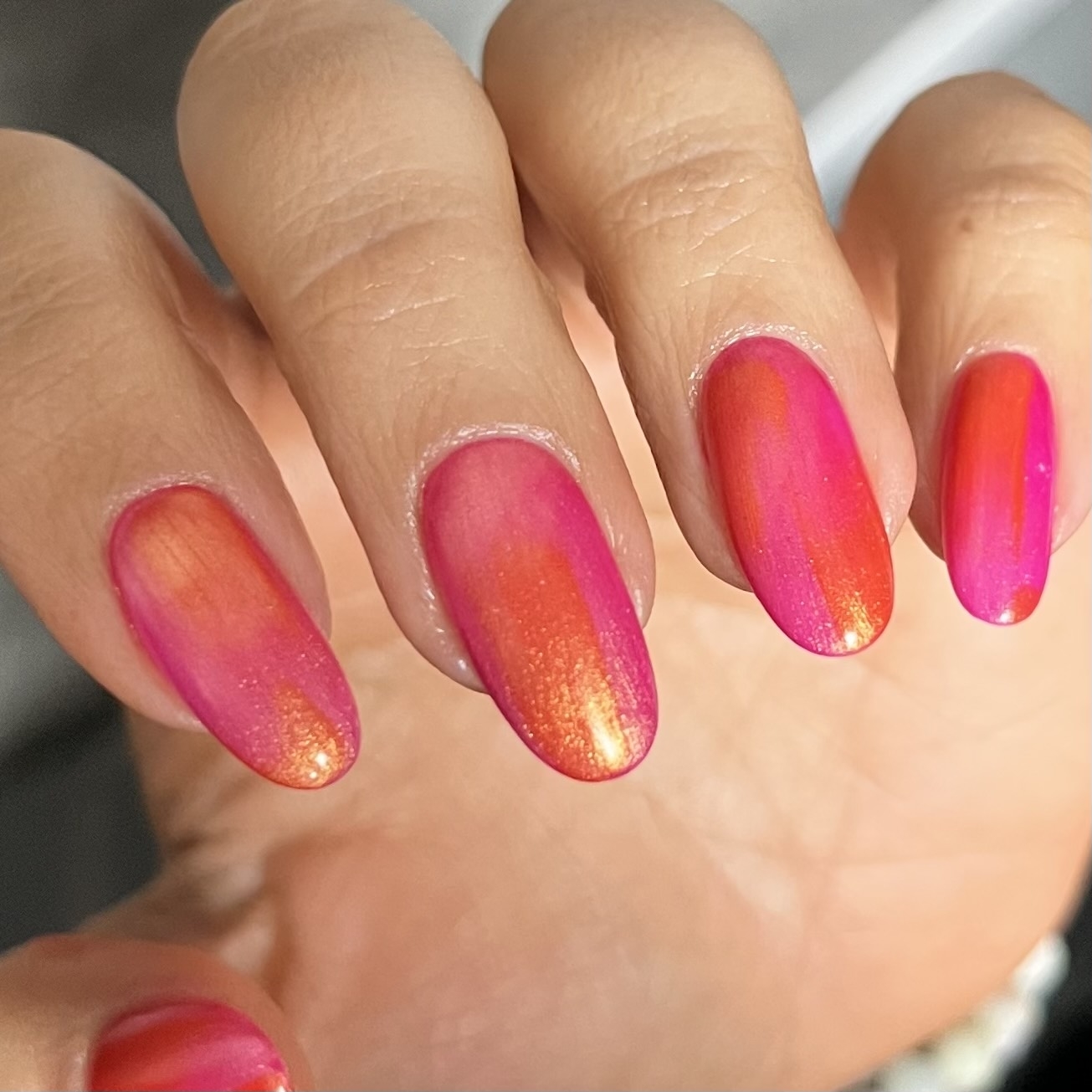 Hand displaying nails with a gradient polish from purple to orange
