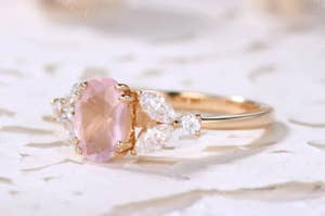 an engagement ring with a large pink stone flanked by diamond stones