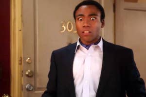 Surprised man in a doorway, wearing a suit sans tie, relevant to a travel-related topic