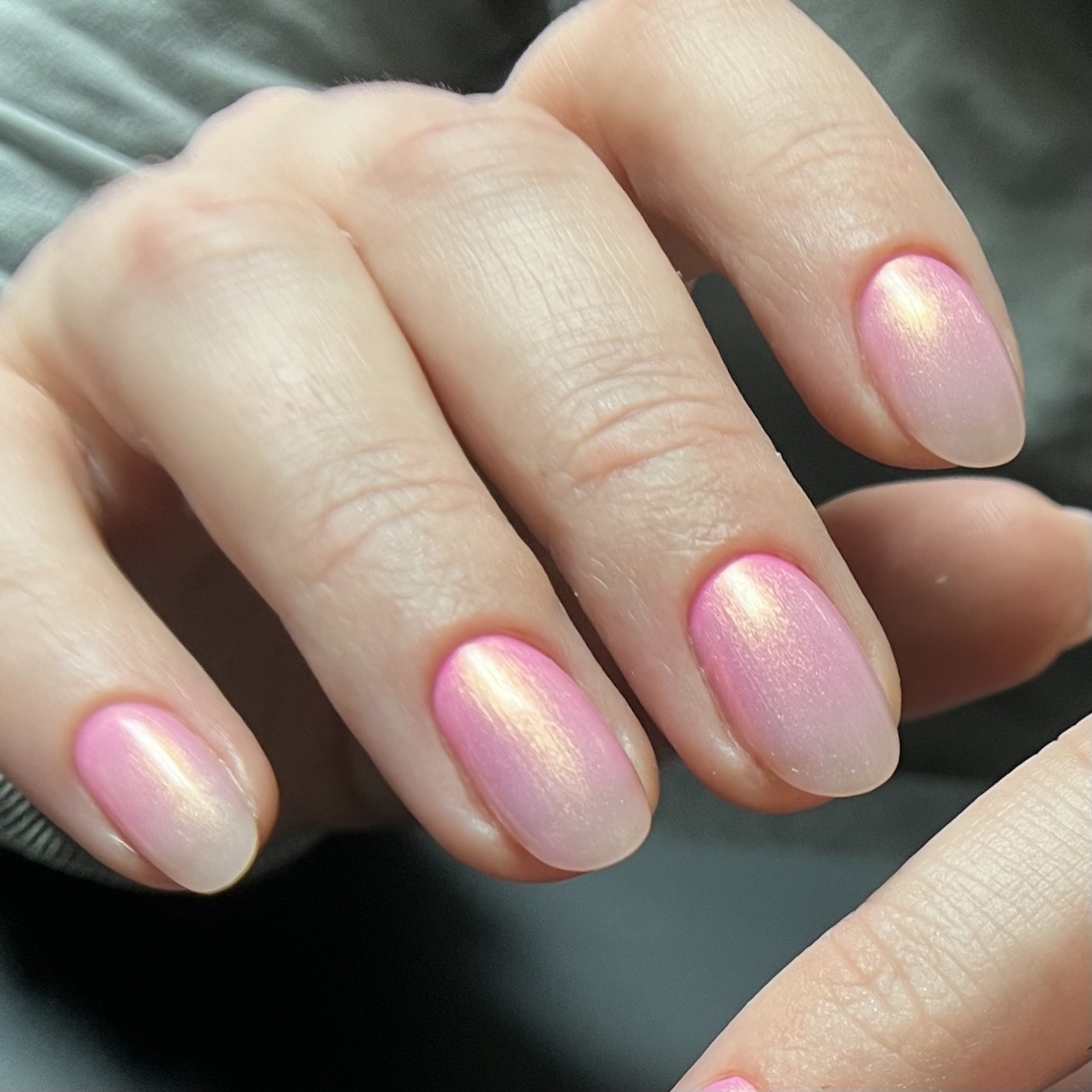 Hand with pink shimmering nail polish on fingernails