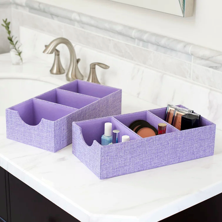 the two boxes in iris heather with cosmetics and toiletries on a bathroom counter