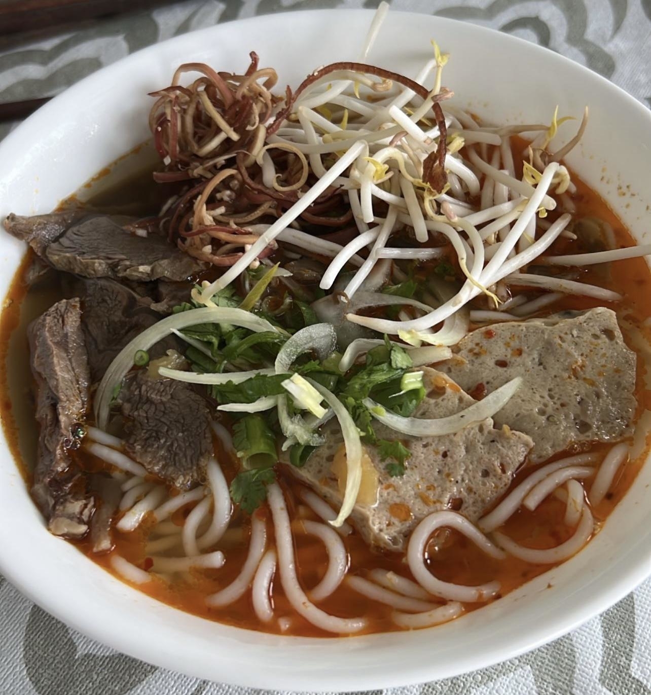 Bowl of Vietnamese Pho with noodles, beef slices, bean sprouts, and herbs