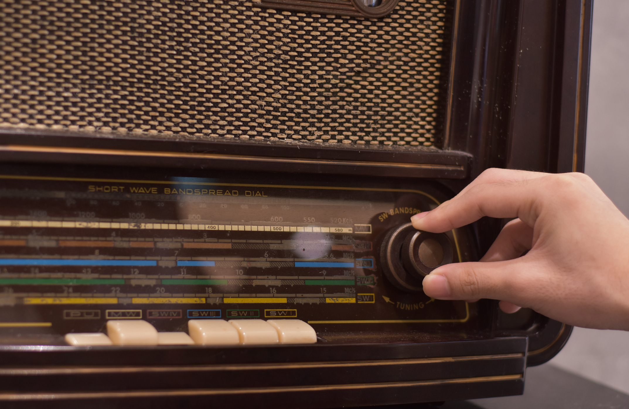 Person tuning an old-fashioned radio with a dial and buttons