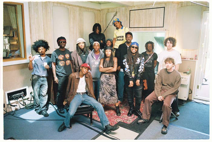 Group of individuals posing together in a room with musical equipment and a poster in the background
