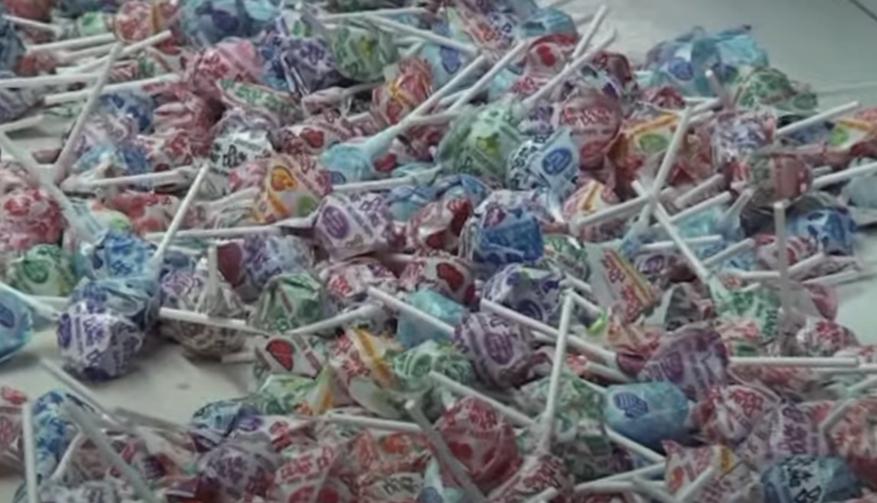 A pile of assorted, unwrapped Dum Dums lollipops scattered on a surface